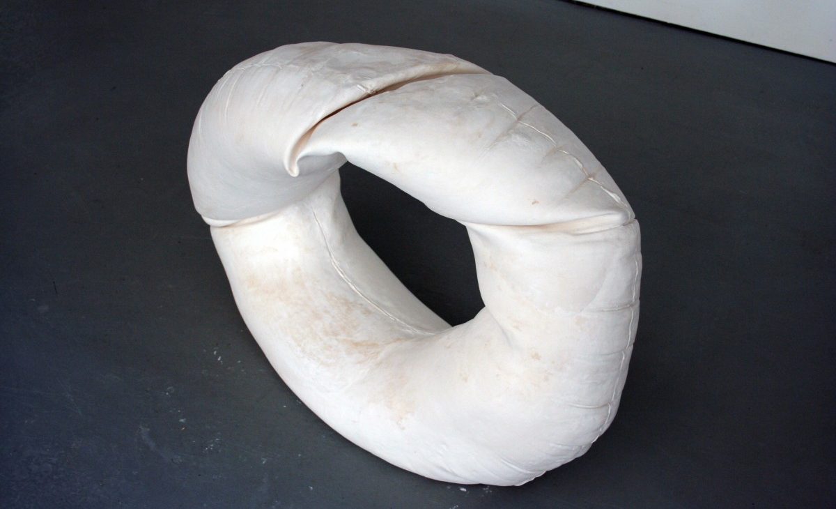 Plaster cast rubber ring with creases; displayed on a grey floor