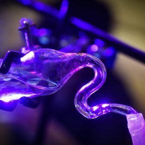 Detail image of scientific glass apparatus with water level in purple lighting against a blurred background