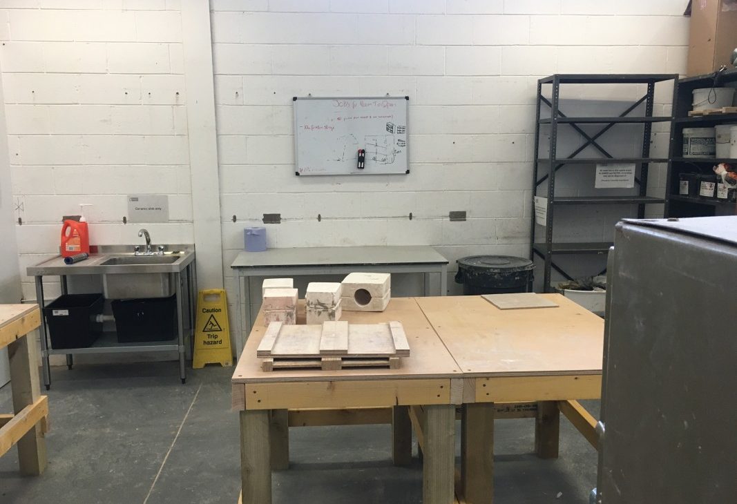 Two work tables sit together in the centre of a workshop with plaster slip cast moulds sitting on top of them