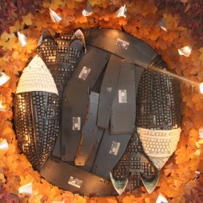 Keyboards cut apart and shaped into two foxes, contained within a ring of lights and autumnal leaves