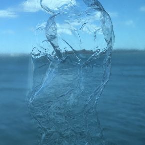Ice figures interlinked over window with sea and sky blurred in the background