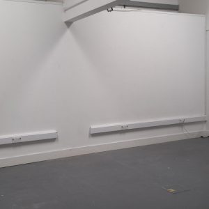 Plain, empty room with white walls and grey painted floor.