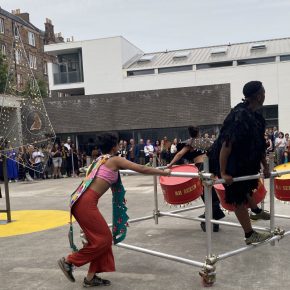 Performers pushing a scaffolding float within a courtyard, Ashanti Harris exhibition