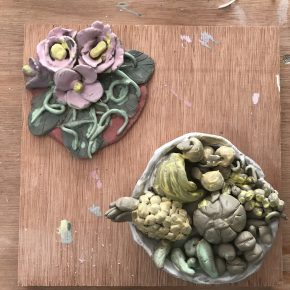 Flower and fruit sculptures made by the MCFB young women's Clay Club sit on a wooden table