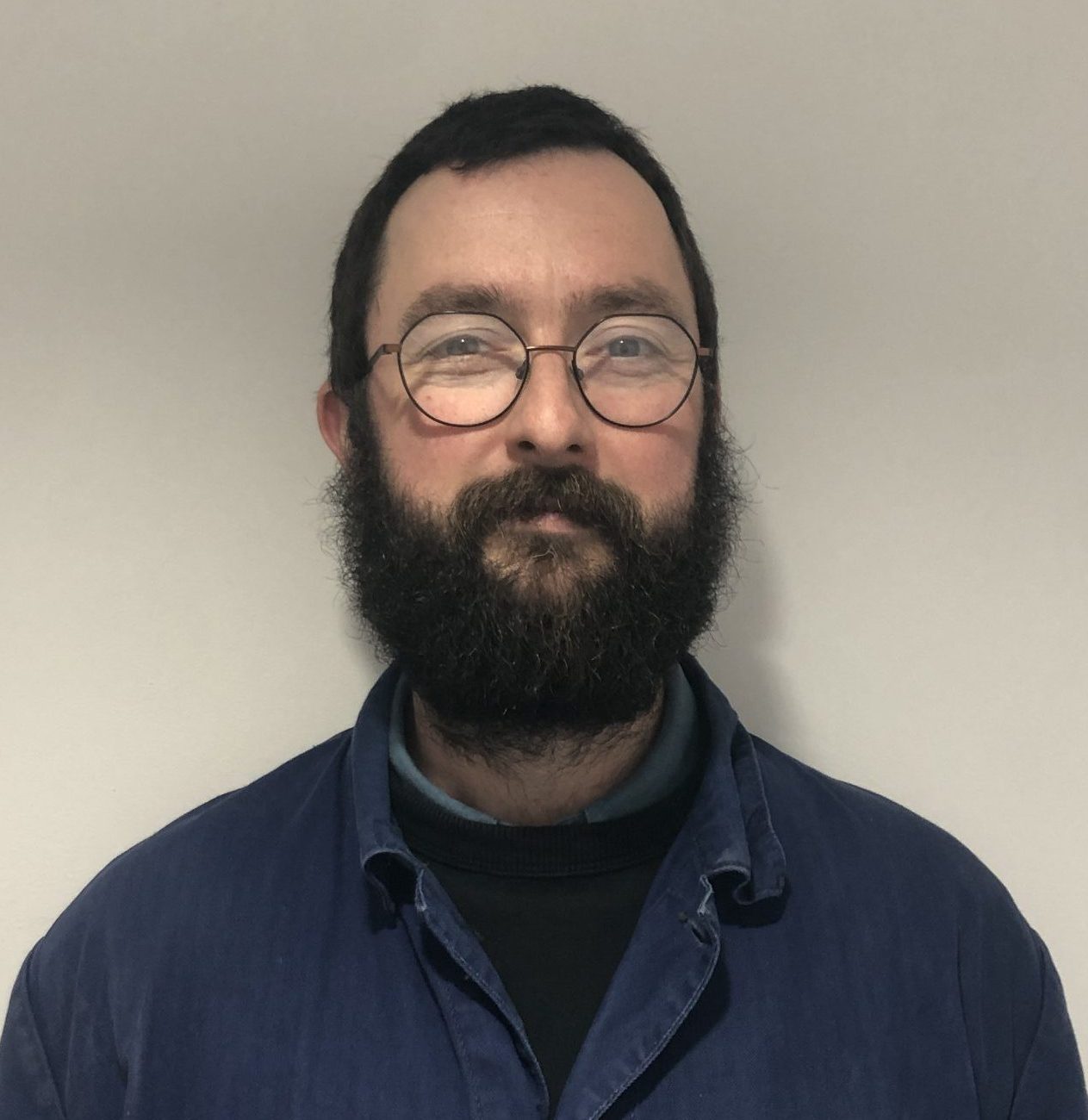 Portrait of Chris Chatham with short dark hair and beard, glasses and navy coat.