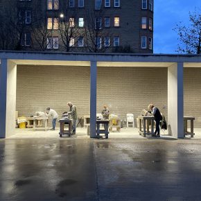 Twilight scene of people working in the Courtyard Bays, illuminated by overhead lights, as part of a Stone Carving Course at ESW.